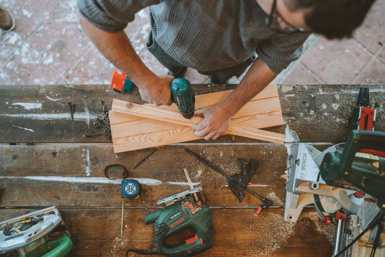 A Man Drilling Hole On A Wood