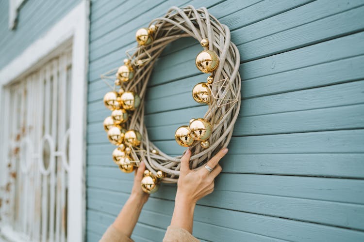 Close-Up Shot Of A Person Hanging A Christmas Wreath