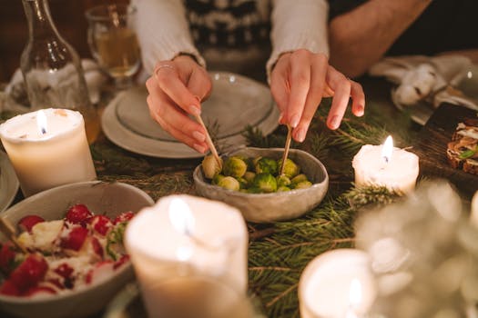 A warm holiday dinner setting featuring brussels sprouts, salad, and candlelight, perfect for seasonal gatherings.