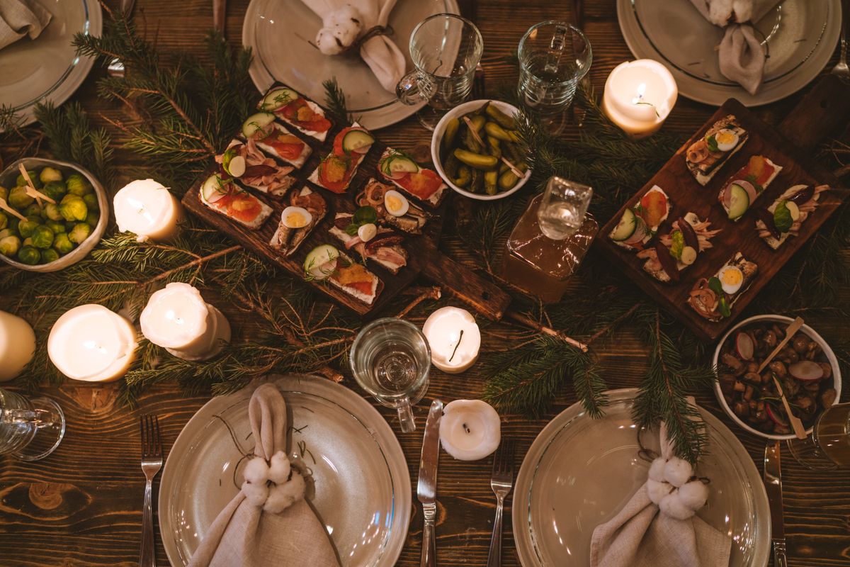 Cozy holiday potluck dinner table with candles and appetizers