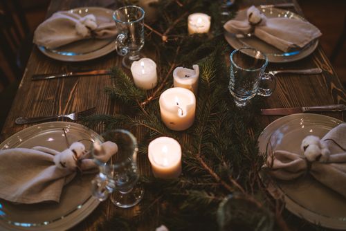 Free Warm and elegant Christmas table with candles, glassware, and pine decor for festive dining. Stock Photo