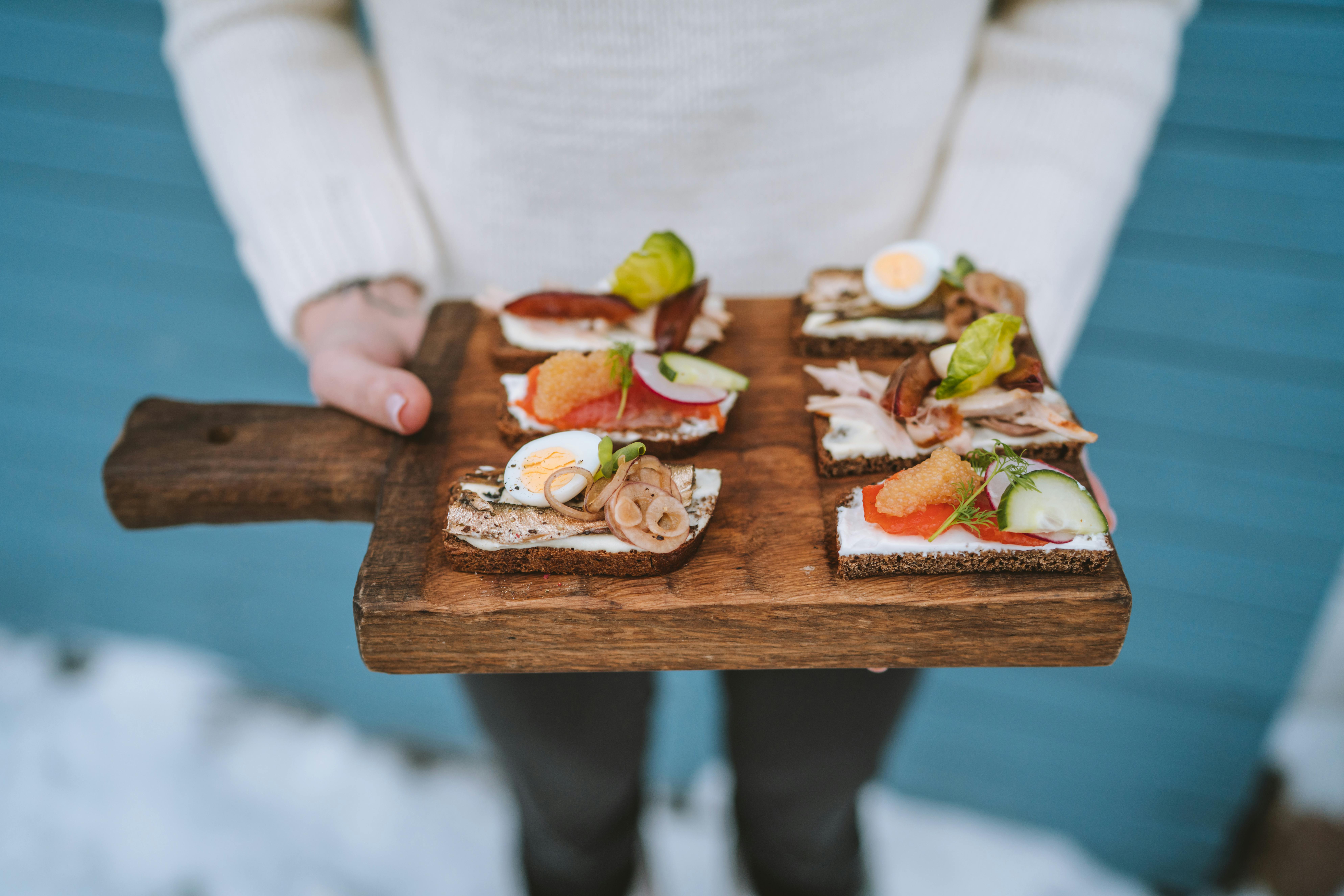 A person holding a wooden tray of food