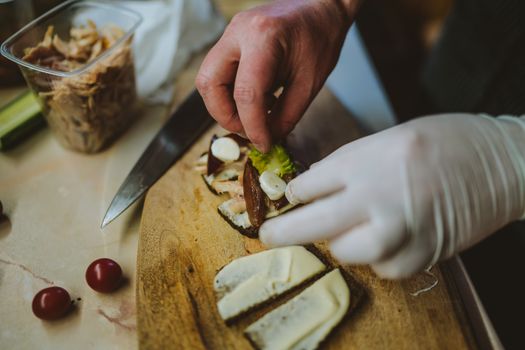 A chef arranges gourmet ingredients on bread slices, showcasing culinary precision.