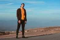 Man in Orange Jacket Standing on Gray Asphalt Road