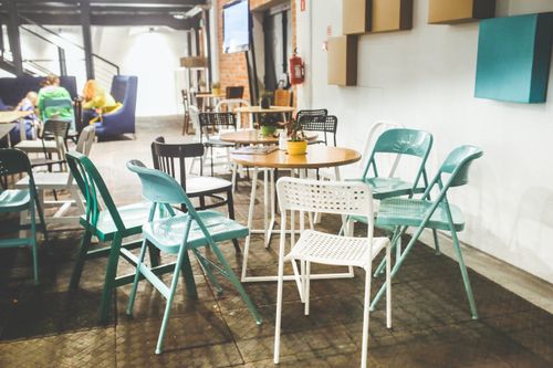 Free Modern bistro interior with colorful chairs and tables, creating a vibrant dining atmosphere. Stock Photo