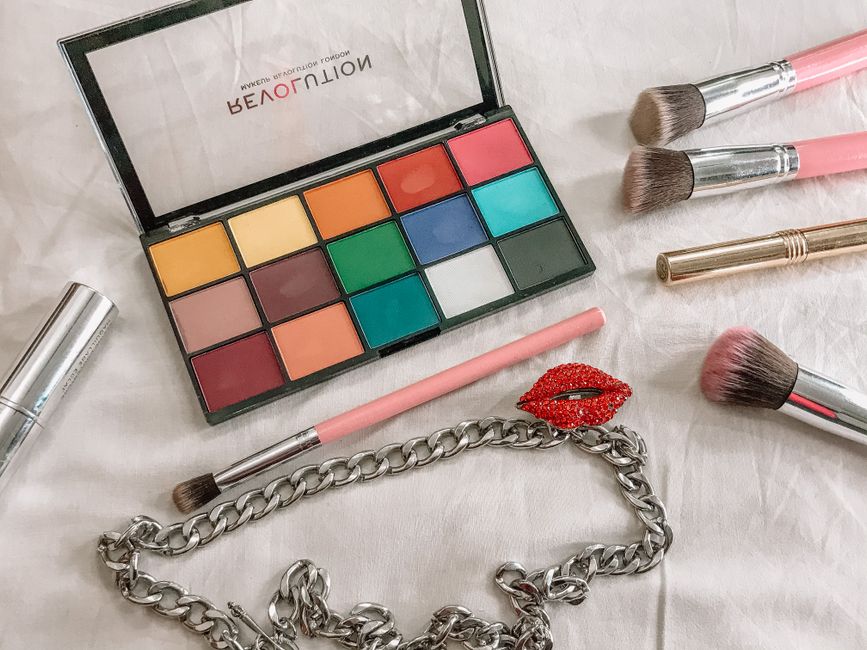 From above of colorful professional makeup palettes arranged with different brushes for visage near stylish accessory
