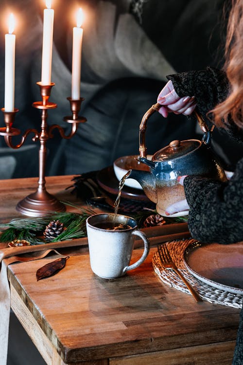 A Woman in Black Long Sleeve Shirt Holding Blue and Brown Ceramic Teapot