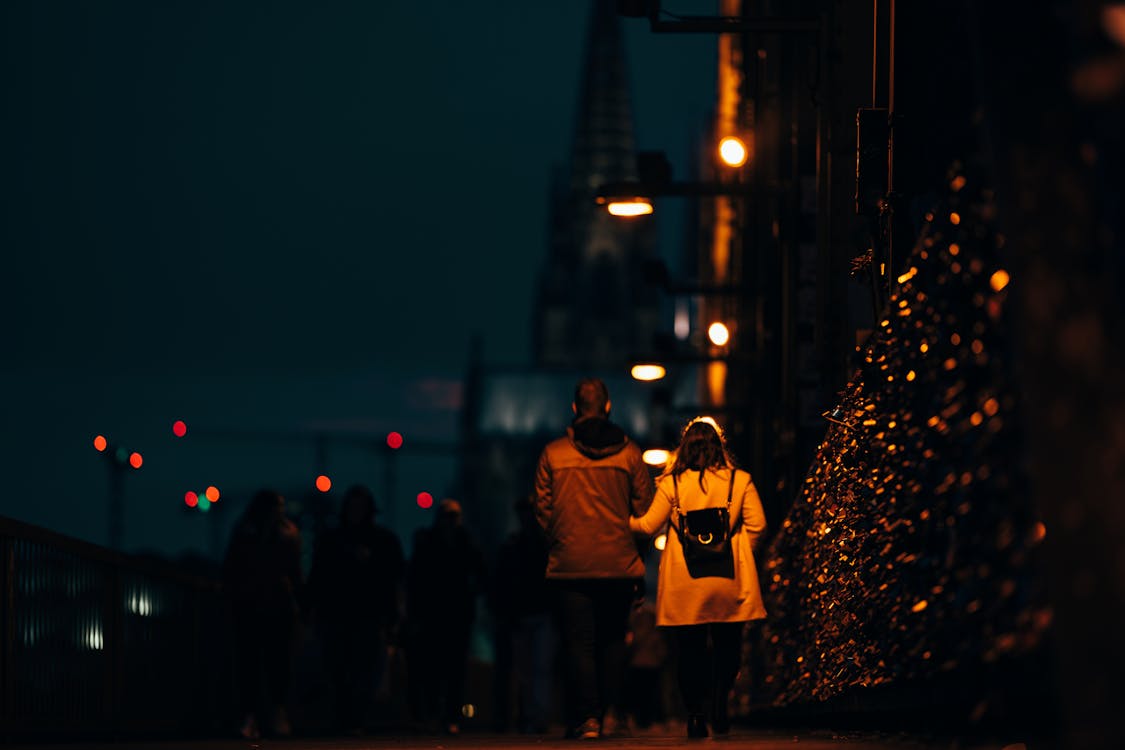 Free A Couple Walking On Sidewalk Of A Street During Night Time Stock Photo