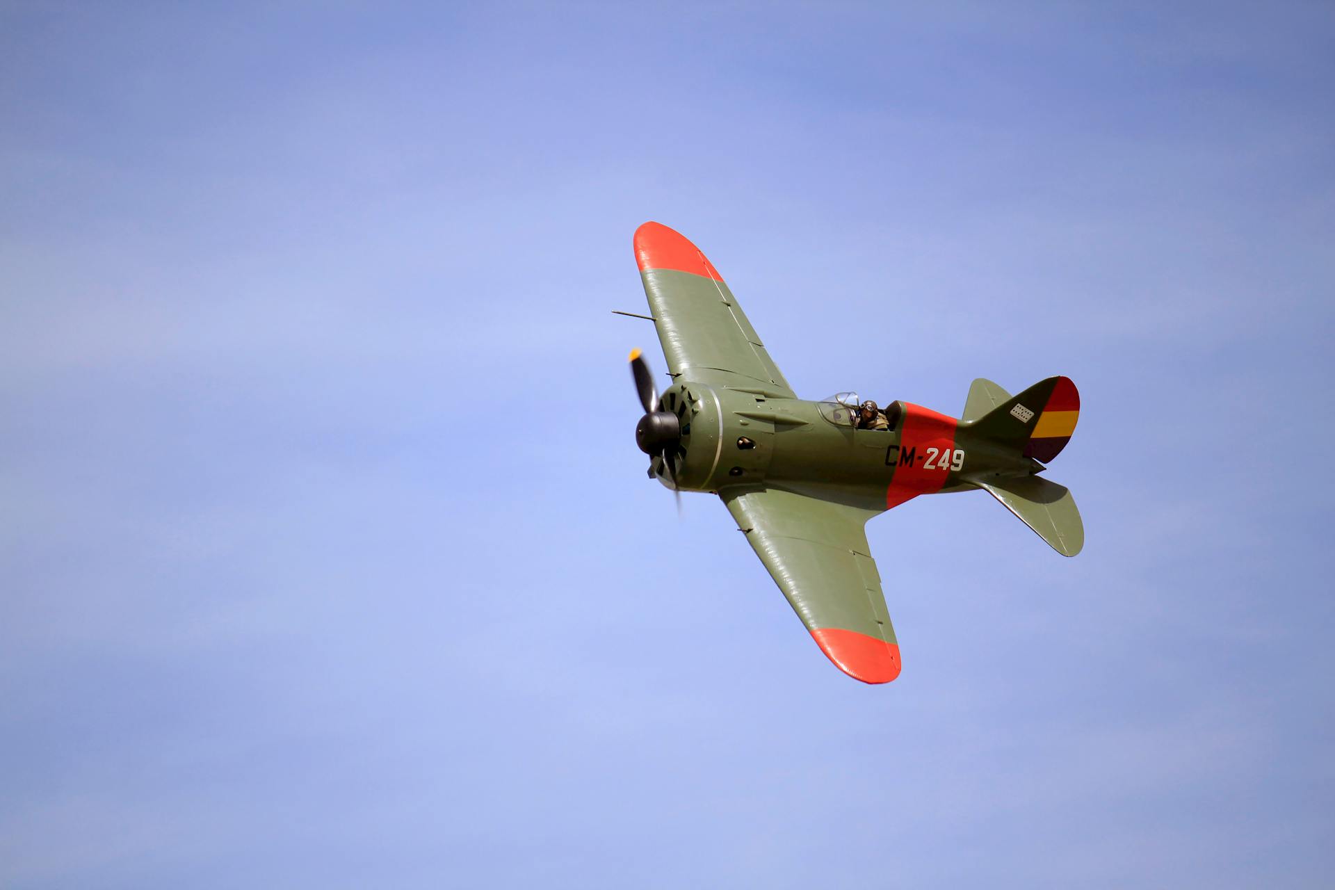 A classic military fighter jet CM-249 executes aerobatic maneuvers against a clear blue sky.