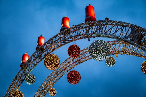 Free Colorful Hanging Decorations with Lights on the Arch Under Blue Sky Stock Photo