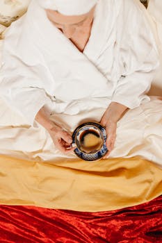 Relaxing morning scene with a person in bathrobe holding coffee, embodying comfort and warmth.