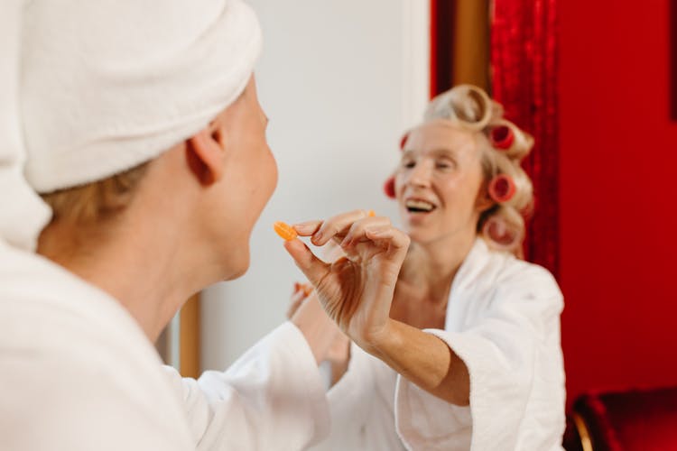 Elderly Women In White Bathrobes Sharing Candies