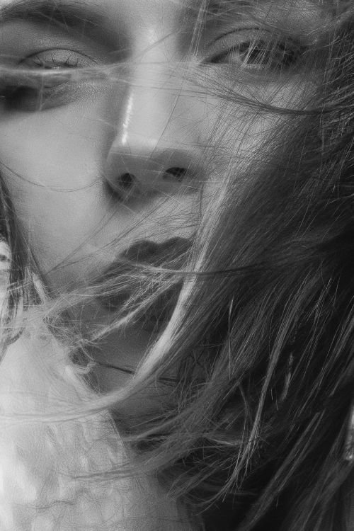 Free Dramatic black and white close-up portrait with flowing hair and intense gaze, capturing emotional depth. Stock Photo