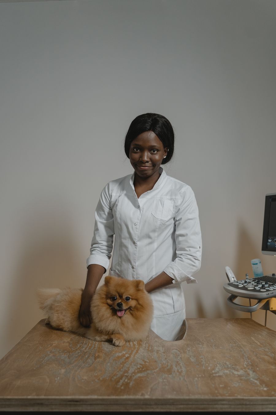 Smiling woman veterinarian Dr. Amara Osei in a white coat with a Pomeranian