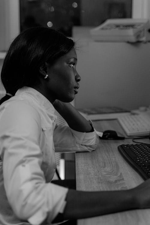 Black and White Photo of a Woman Using Computer