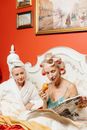 A Woman in a Nightgown Eating Croissant while Reading the Newspaper
