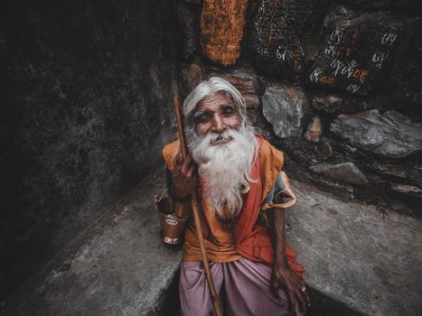 An elderly man with a long white beard holding a stick in Kathmandu, Nepal.