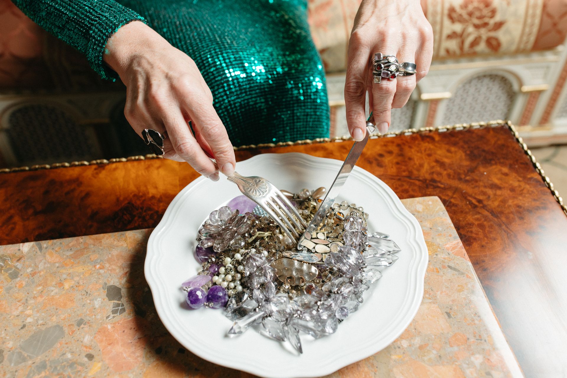 A unique dining setting featuring a plate of gems and jewelry on a marble table.
