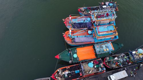 Free Aerial view of vibrant fishing boats docked at a shore in Vietnam. Stock Photo