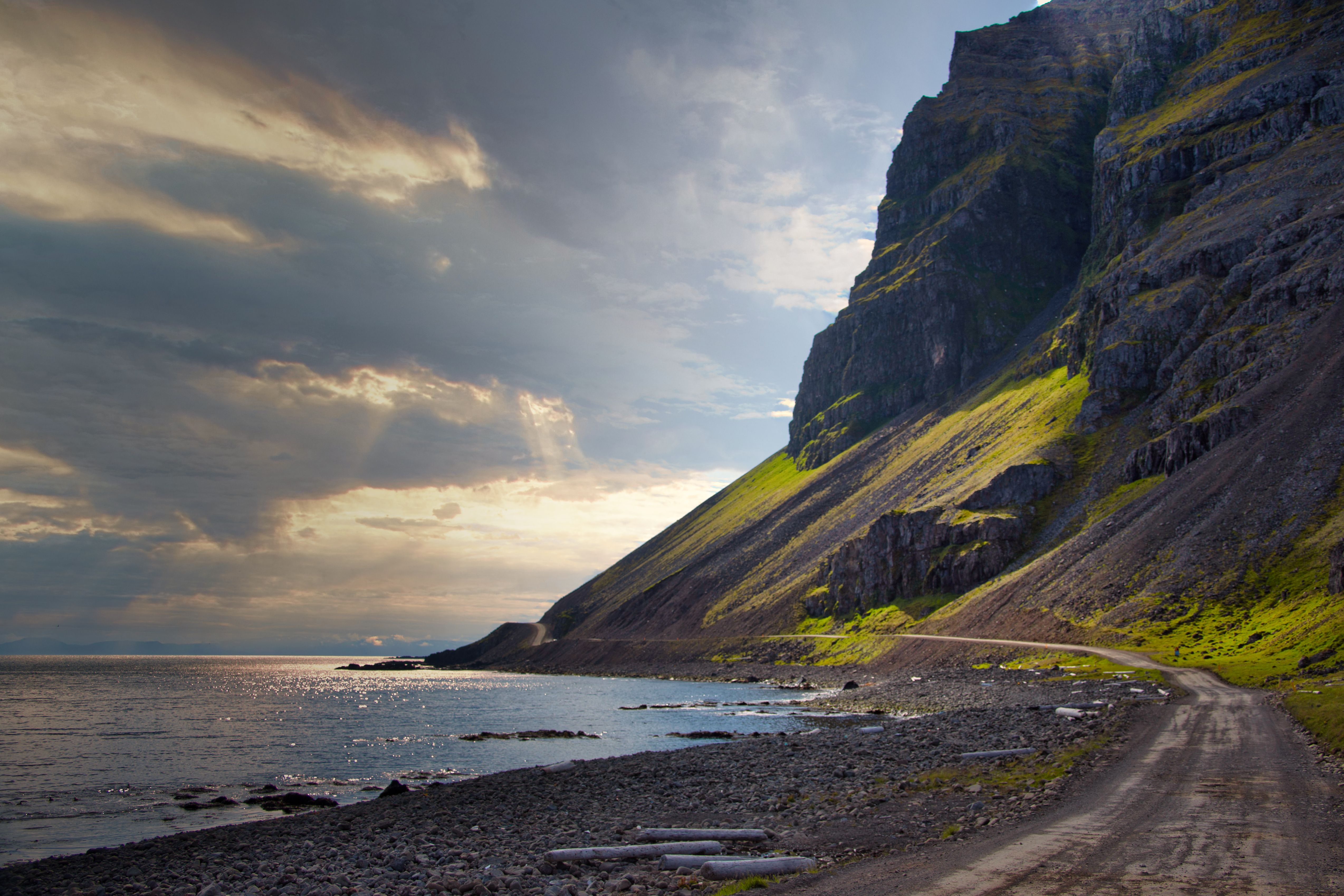 Dramatic Icelandic coastline with cliffs and dirt road under cloudy sky. — photo by Koen Swiers / Pexels