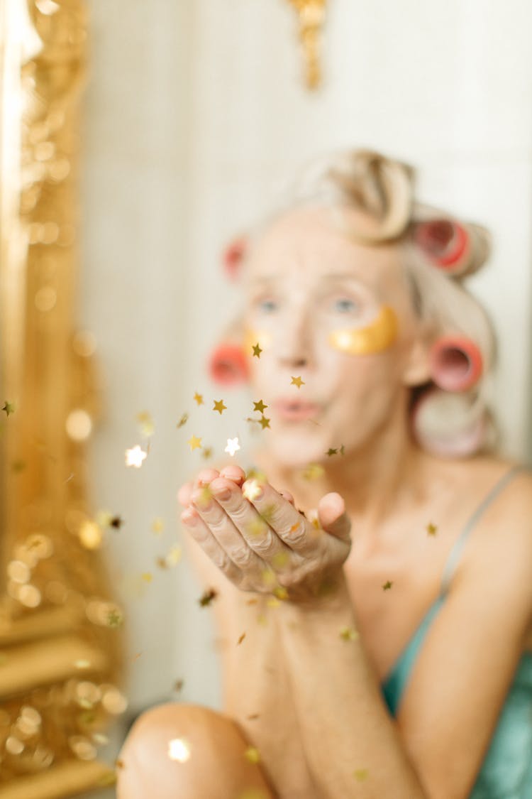 Shallow Focus Photo Of Gold Confetti Stars Blown By A Woman 