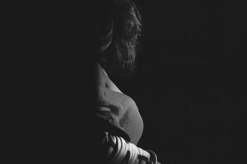 Free Artistic side view silhouette of a woman in a shadowy studio setting. Stock Photo