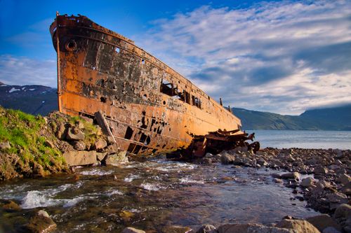 Free Abandoned rusty shipwreck on the shore of Djúpavík, Iceland, with a serene seaside backdrop. Stock Photo