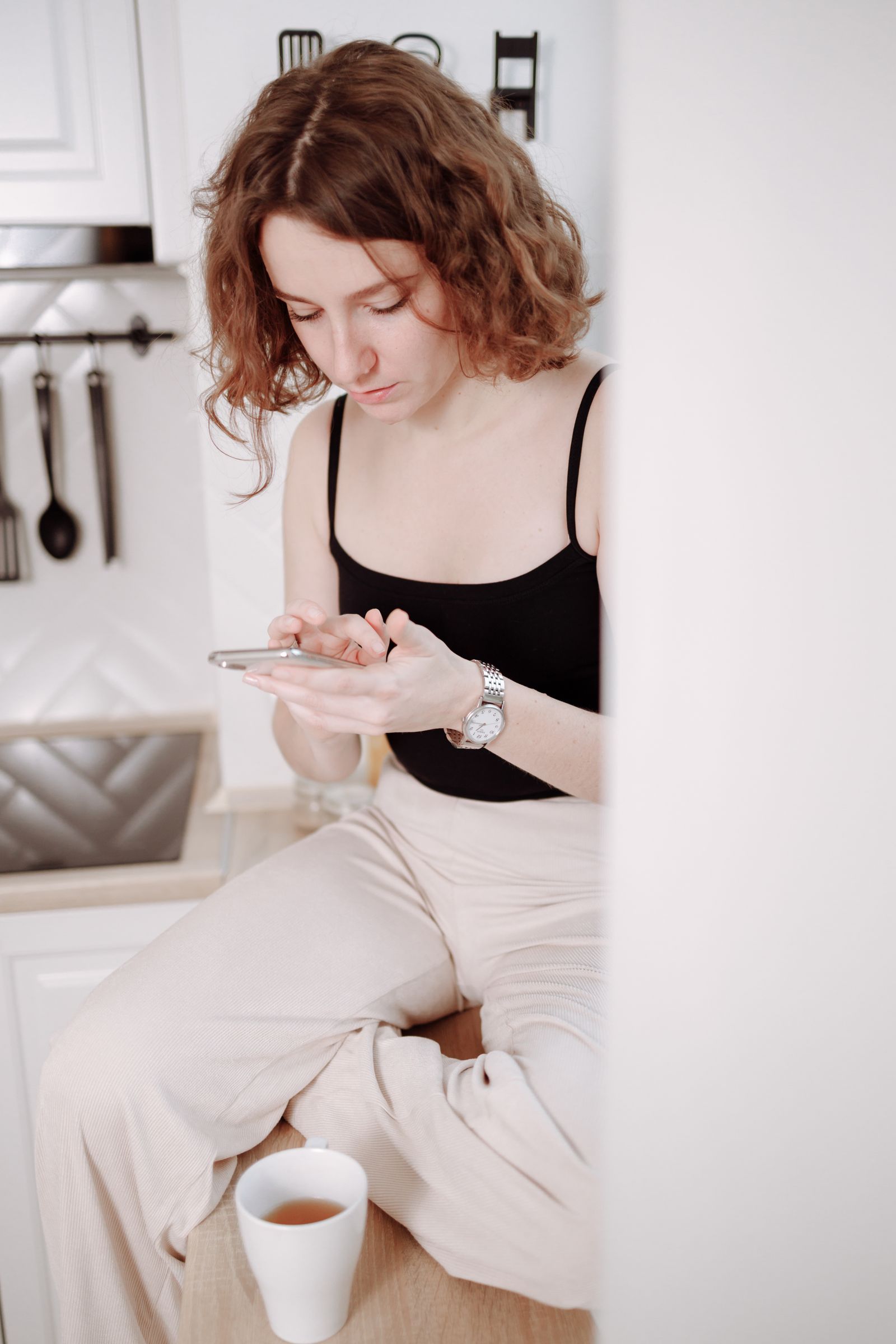 A visitor at home with a cup of tea, typing a question into her phone
