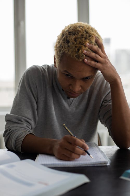 Thoughtful black man writing in notepad