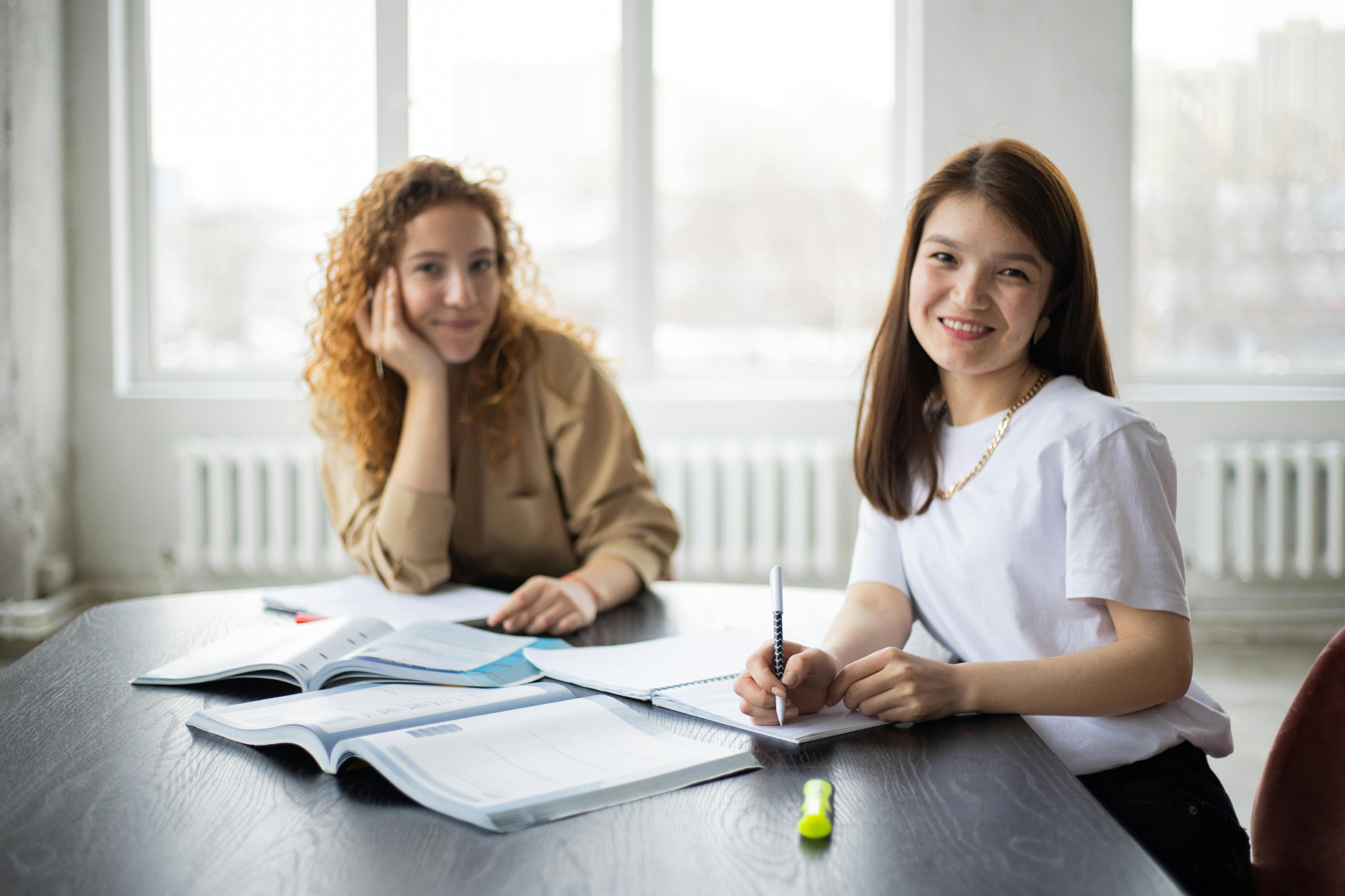 cheerful diverse women with copybooks at table