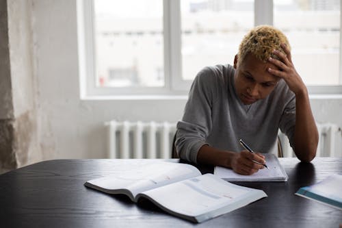 Wistful black man writing in notepad during lesson