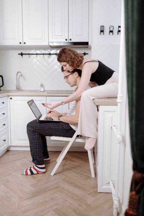 Free A couple in a cozy kitchen engaged in online shopping on a laptop. Stock Photo