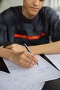 Crop black man writing on paper in classroom