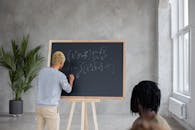 Anonymous black man writing equation on chalkboard