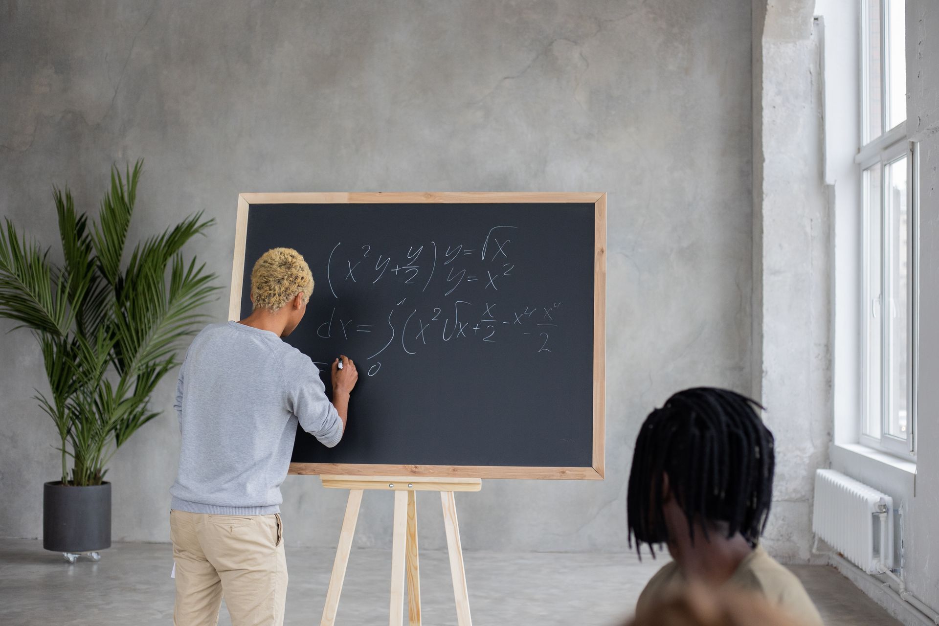 Young student writing complex equations on a blackboard during math class indoors.