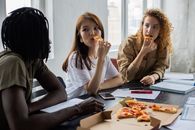 Multiethnic students eating pizza during break in studies