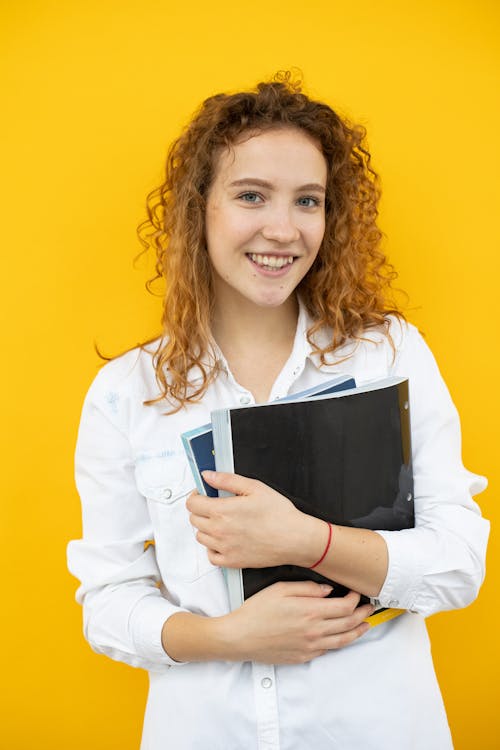 Cheerful woman with folder and textbook