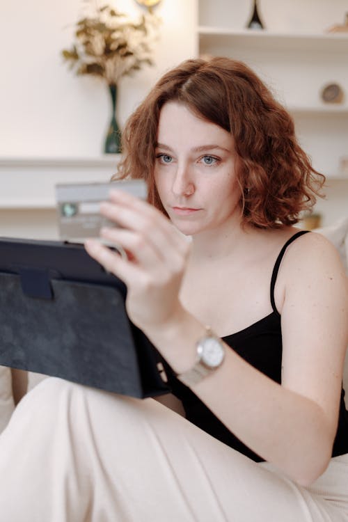 Free Woman Holding a Credit Card While Using a Tablet Stock Photo