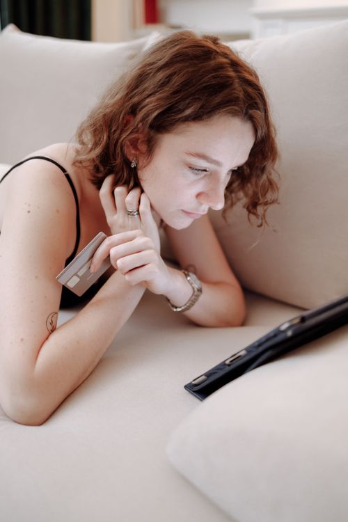 Free Young woman using a tablet for online shopping at home, holding a credit card. Stock Photo