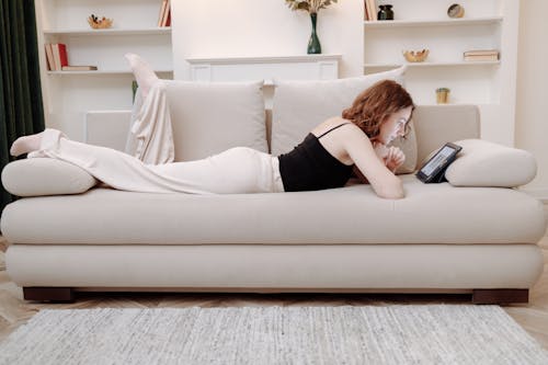 Free Woman Lying on a Couch while Shopping Online Stock Photo