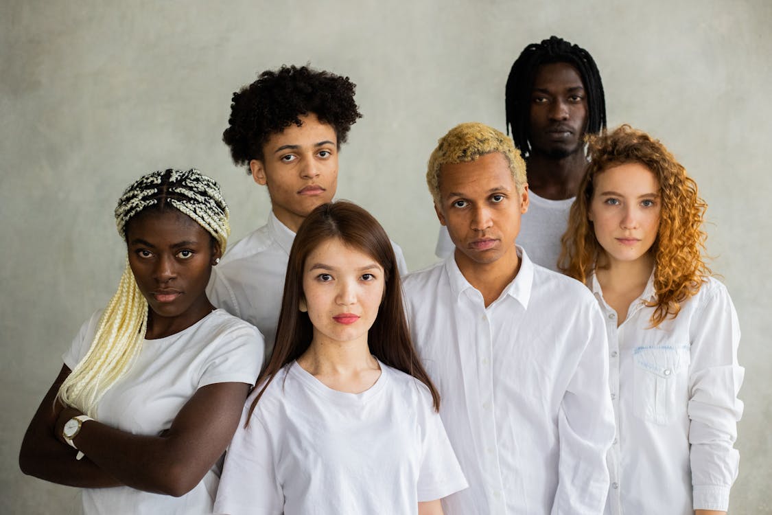Free Serious diverse multiracial people standing close together representing concept of unity  and looking at camera against gray background Stock Photo