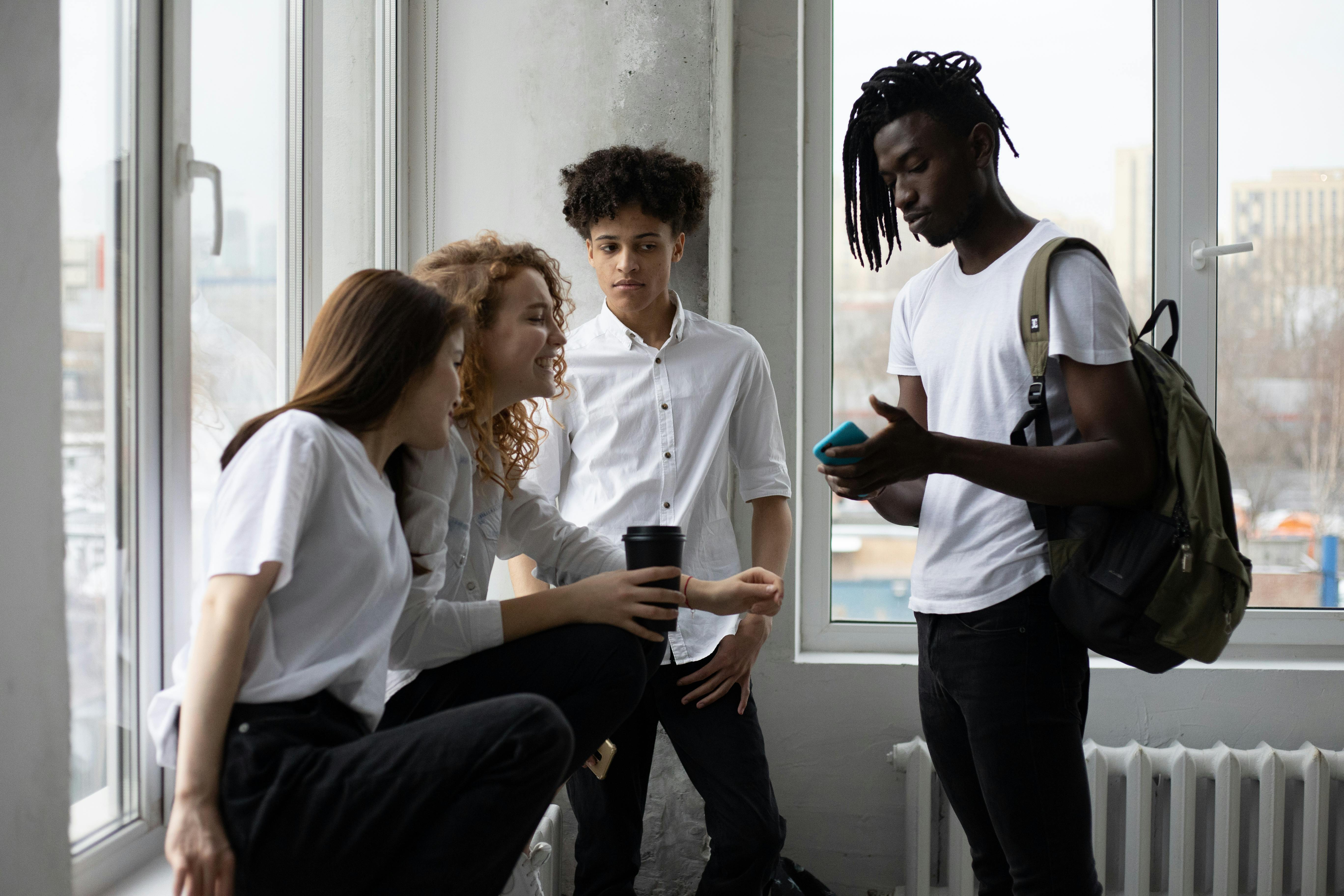 young diverse students chatting near window