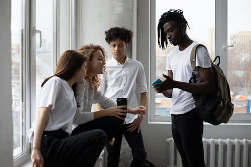 Free Young diverse students chatting near window Stock Photo
