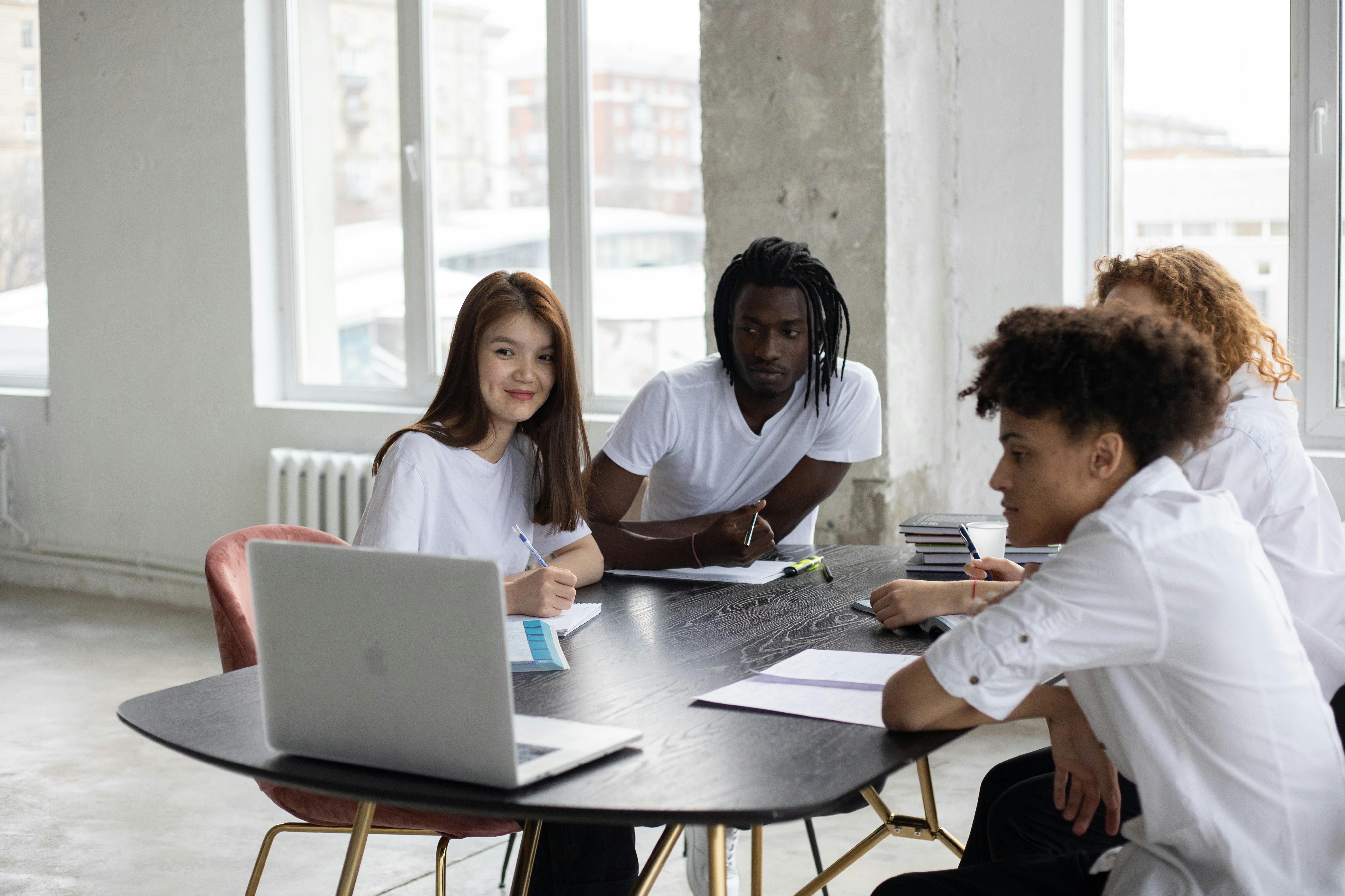 multiethnic students gathering around table with laptop