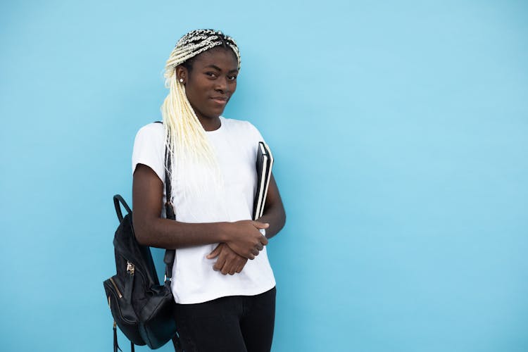 Positive Black Woman With Books And Backpack In Studio