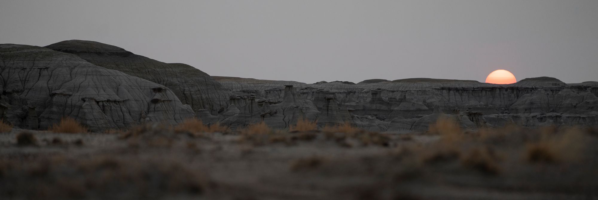 Formaciones erosionadas de arcilla y arenisca en un desierto de badlands bajo cielo despejado en Nuevo México