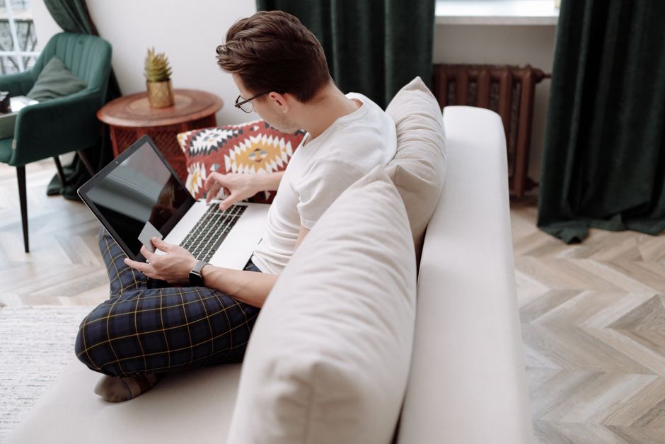 Man working on a laptop while sitting on a comfortable sofa in a modern, stylish room. Man working on a laptop while sitting on a comfortable sofa in a modern, stylish room.