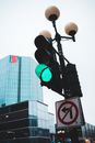 From below of green traffic light on lamp post with forbidden road sign representing arrow in red circle in town