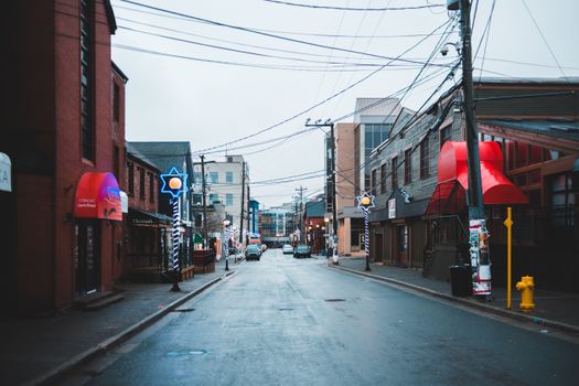 A modern urban street featuring colorful neon signs and empty road on a cloudy day, creating a vibrant atmosphere.