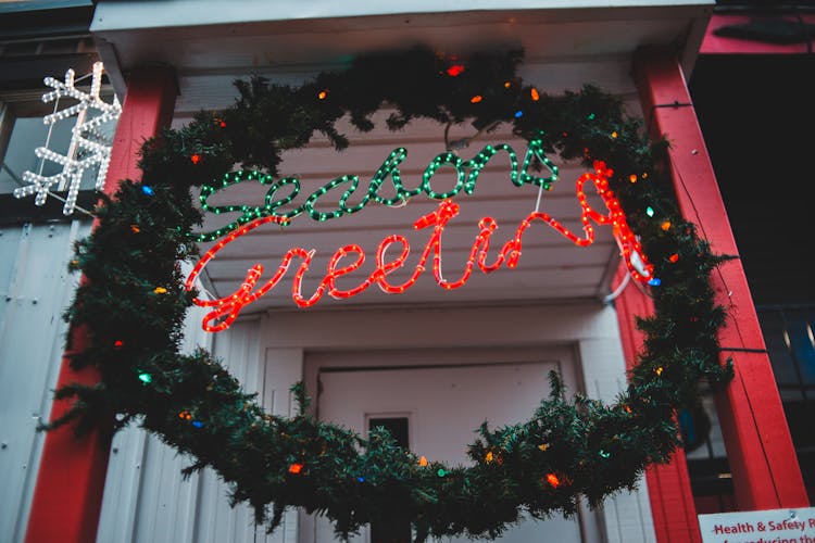 Christmas Wreath With Seasons Greeting Inscription On House In Town